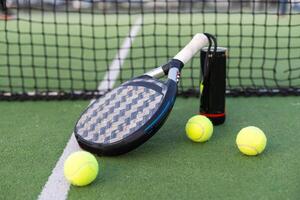 peddelen tennis racket, bal en netto Aan de gras foto