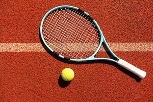 racket met een tennis bal Aan een rood klei rechtbank. foto