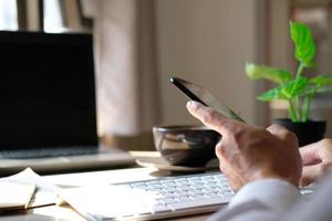 close-up van de handen van een man genomen met behulp van een smartphone, in het café, een man is op zijn telefoon en typt berichten op sociale media. foto