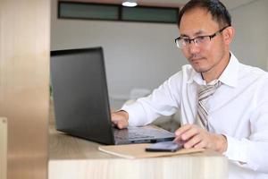 jonge zakenman die een laptopcomputer gebruikt aan zijn bureau in een modern kantoor foto