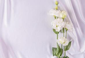 delicaat bruiloft achtergrond voor ontwerp, kaart, uitnodiging. wit vouwen van de satijn kleding stof en wit vers bloemen. romantisch ontwerp. een kopiëren ruimte foto