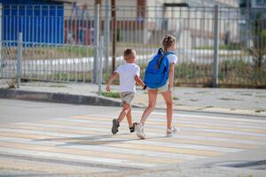 broer en zus rennen aan de overkant een voetganger kruispunt. kinderen rennen langs de weg naar kleuterschool en school.zebra verkeer wandelen manier in de stad. concept voetgangers voorbijgaan een zebrapad foto