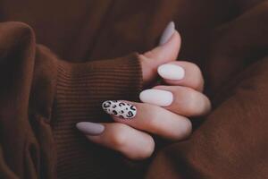 vrouw hand- met een mooi ovaal van vorm manicuren. herfst tendens, beige kleur polijsten met luipaard patroon Aan nagels met gel Pools, schellak. foto