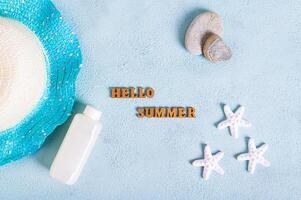 concept Hallo zomer tekst, hoed, zonnebrand lotion, stenen en zeester Aan blauw top visie foto