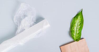 papier zak met vers blad en rollen van plastic Tassen Aan blauw achtergrond web banier foto