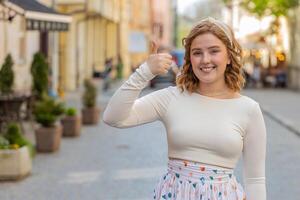 gelukkig vrouw tonen duimen omhoog Leuk vinden teken positief iets mooi zo positief terugkoppeling in stad straat foto