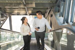 twee professionals in gesprek terwijl rijden een roltrap foto