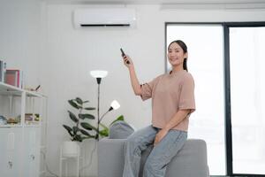 jong vrouw controlerend lucht conditioner Bij huis foto