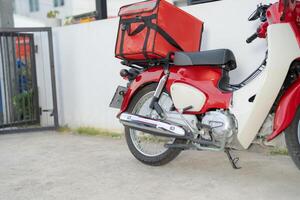 rood levering motorfiets met geïsoleerd voedsel doos geparkeerd buitenshuis foto