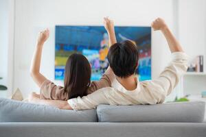 paar genieten van sport- bij elkaar passen Aan televisie Bij huis foto