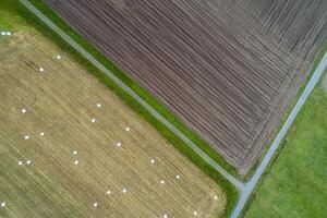 agrarisch velden, een veld- geploegd voor aanplant en een ander geoogst met ronde rietje balen. antenne top visie foto