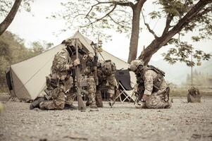 soldaten in camouflage uniformen planning Aan operatie in de kamp, soldaten opleiding in een leger operatie foto