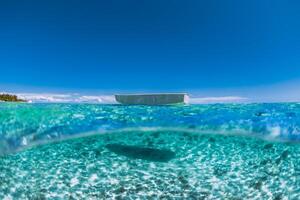 turkoois oceaan met zanderig bodem in tropen en boot foto
