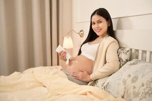 mooi zwanger vrouw toepassen hydraterend, rekken Mark room Aan buik, vruchtbaarheid onvruchtbaarheid behandeling, ivf, toekomst moederschap concept foto