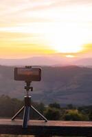 een smartphone is opname de zon instelling over- een berg bereik. foto