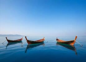 drie houten boten drijvend Aan een kalm, blauw meer met een Doorzichtig blauw lucht in de achtergrond foto