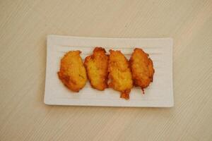 maïs kroketten Aan een wit bord Aan een houten tafel foto