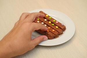 chocola bars met kleurrijk snoepjes Aan een wit bord in hand- foto