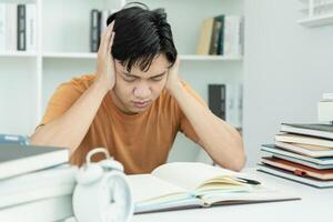 Aziatisch leerling Mens hebben ongerustheid omdat van examens, mannetje bereiden voor test en aan het leren lessen in de bibliotheek. spanning, wanhoop, haast, misverstand lezing, ontmoedigd, verwachting, kennis, moe foto