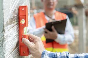 contactor of ingenieur is inspecteren bouw en kwaliteit zekerheid nieuw huis gebruik makend van een niveau. ingenieurs of architecten of contactor werk naar bouwen de huis voordat overhandigen het over- naar de huiseigenaar foto