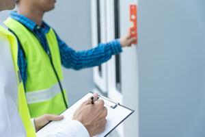 contactor of ingenieur is inspecteren bouw en kwaliteit zekerheid nieuw huis gebruik makend van een niveau. ingenieurs of architecten of contactor werk naar bouwen de huis voordat overhandigen het over- naar de huiseigenaar foto