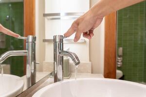 opslaan water. vrouw houdt draaien uit de rennen water in de badkamer naar beschermen omgeving. vergroening planeet, verminderen globaal opwarming, opslaan wereld, leven, toekomst, risico energie, crisis , water dag. foto