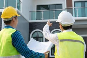 inspecteur of ingenieur is inspecteren bouw en kwaliteit zekerheid nieuw huis gebruik makend van een blauw afdrukken. ingenieur of architecten of contactor werk naar bouwen de huis voordat overhandigen het over- naar de huiseigenaar foto