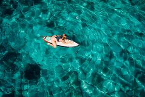 surfer vrouw Aan surfboard in tropisch oceaan. antenne top visie foto