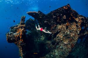 vrouw vrij duiker zwemmen met vinnen Bij wrak schip. gratis duiken in oceaan foto