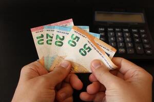 Mens tellen euro geld met zijn hand. euro bankbiljetten. de papier valuta van europees unie .rekenmachine in de achtergrond. foto