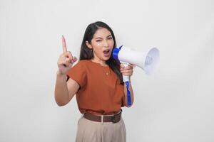 opgewonden Aziatisch vrouw vervelend een bruin overhemd tonen aantal een met vinger geschreeuw en schreeuwen luid gebruik makend van megafoon spreker. communicatie concept. foto