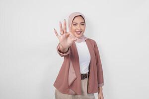 glimlachen Aziatisch moslim vrouw in hijab geven een Oke hand- gebaar geïsoleerd over- wit achtergrond. foto