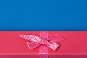 top visie van een rood geschenk doos met lint en boog Aan een blauw achtergrond met kopiëren ruimte foto