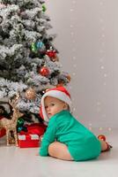 baby in Kerstmis gnoom kostuum opent cadeaus in de buurt Kerstmis boom. producten voor kinderen en vakantie foto