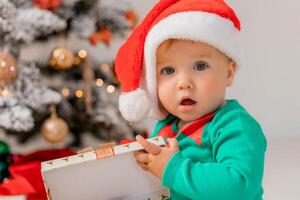 baby in Kerstmis gnoom kostuum opent cadeaus in de buurt Kerstmis boom. producten voor kinderen en vakantie foto