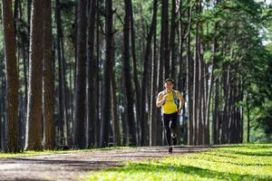 Aziatisch spoor loper is rennen buitenshuis in de pijnboom Woud aarde weg met water rugzak voor oefening activiteiten opleiding naar ras in de ultra marathon naar bereiken gezond levensstijl en geschiktheid foto