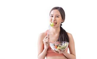 Aziatisch vrouw in sportkleding Holding kom van vers salade voor gezond aan het eten en veganistisch cultuur van consumptie concept foto
