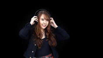portret van jong Aziatisch vrouw zetten koptelefoon Aan geïsoleerd Aan zwart achtergrond voor lied en audio stem Vermelding voor muziek- en vermaak bedrijf foto