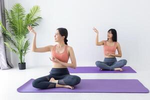 Aziatische vrouw die binnen yoga beoefent met een gemakkelijke en eenvoudige positie om het in- en uitademen in meditatiehouding te regelen foto