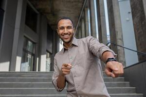 dichtbij omhoog van zakenman dansen blij vieren zege en succes, Mens buiten kantoor gebouw op zoek Bij camera. foto