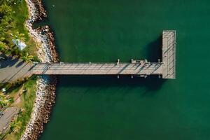 top visie van houten pier en stil zee met zon licht, antenne visie foto