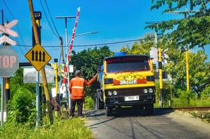 schoon water tanker vrachtauto bestuurder wie geeft tips naar trein kruispunt poort bewakers, Indonesië, 4 mei 2024. foto