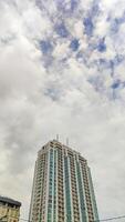 een hoog stijgen gebouw appartement met bewolkt lucht kopiëren ruimte, Indonesië, 17 april 2024. foto