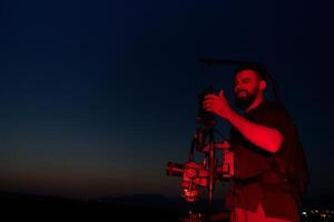 's nachts vastleggen. professioneel videograaf films atleten rennen in rood verlicht duisternis foto