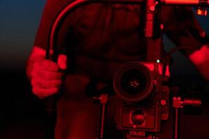 's nachts vastleggen. professioneel videograaf films atleten rennen in rood verlicht duisternis foto