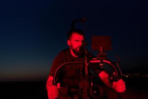's nachts vastleggen. professioneel videograaf films atleten rennen in rood verlicht duisternis foto