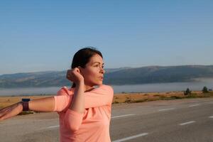 vastbesloten rekken. atletisch vrouw omarmt post-run flexibiliteit in natuur. foto