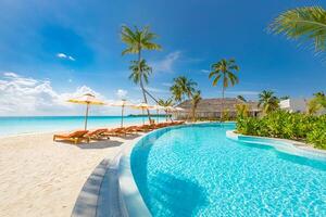 outdoor toerisme landschap. luxe strandresort met zwembad en strandstoelen of ligstoelen onder parasols met palmbomen en blauwe lucht. zomer reizen en vakantie achtergrond concept foto