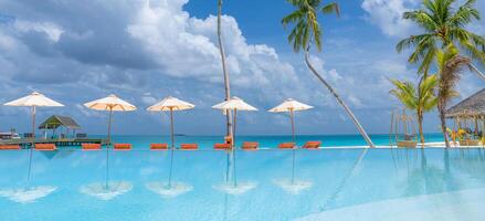 outdoor toerisme landschap. luxe strandresort met zwembad en strandstoelen of ligstoelen onder parasols met palmbomen en blauwe lucht. zomer reizen en vakantie achtergrond concept foto