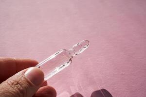 ampul voor injectie met geneesmiddelen Aan een roze achtergrond in hand. foto